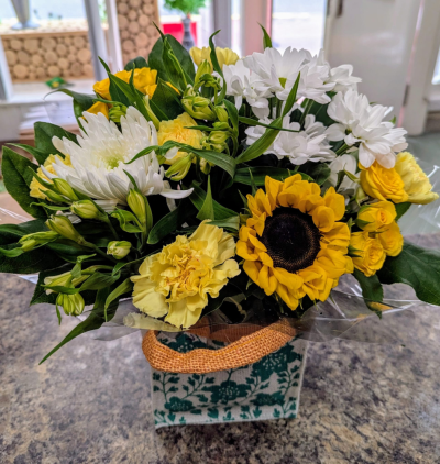 Golden Smile Arrangement - A cheerful gift bag arrangement filled with bright yellow and white seasonal blooms, expertly arranged to bring warmth, colour and a smile to any occasion.